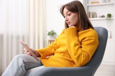 Photo of Woman with modern tablet in armchair at home