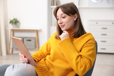 Photo of Woman with modern tablet in armchair at home