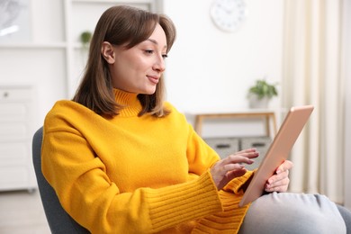 Photo of Woman with modern tablet in armchair at home
