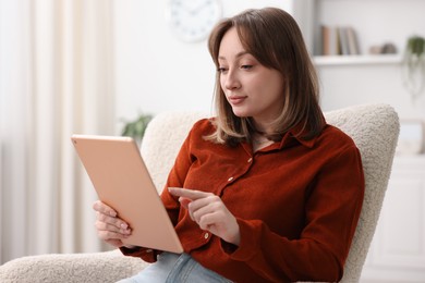 Photo of Woman with modern tablet in armchair at home