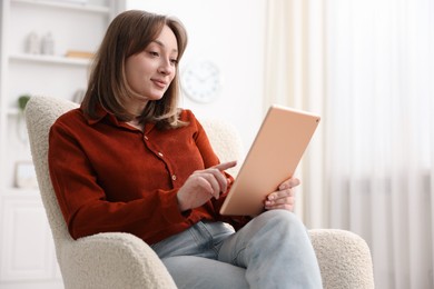 Photo of Woman with modern tablet in armchair at home