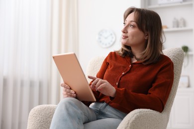 Photo of Woman with modern tablet in armchair at home