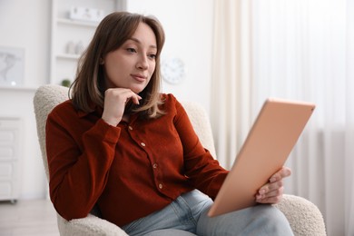 Photo of Woman with modern tablet in armchair at home
