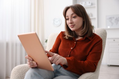 Photo of Woman with modern tablet in armchair at home