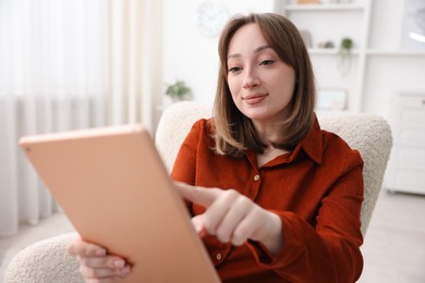 Photo of Woman with modern tablet in armchair at home