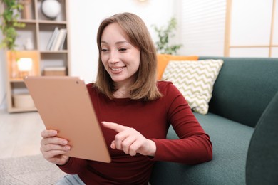 Photo of Woman with modern tablet on floor at home