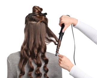 Photo of Hairdresser curling woman's hair on white background, back view
