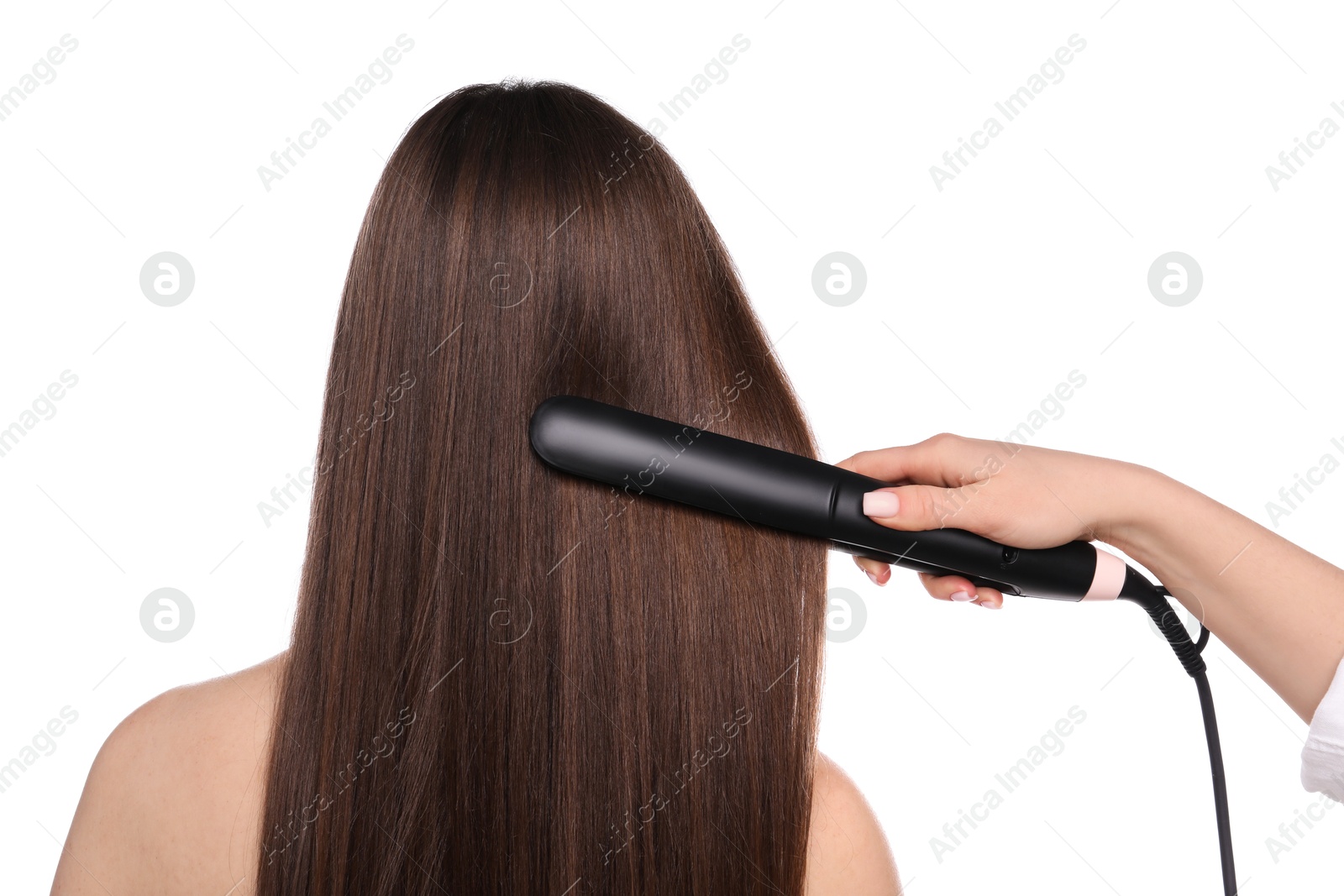 Photo of Hairdresser straightening woman's hair on white background, back view