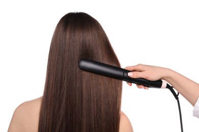 Photo of Hairdresser straightening woman's hair on white background, back view