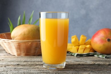 Photo of Tasty mango juice in glass and fresh fruits on wooden table