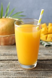 Photo of Tasty mango juice in glass and fresh fruits on wooden table, closeup