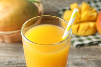 Photo of Tasty mango juice in glass and fresh fruits on table, closeup