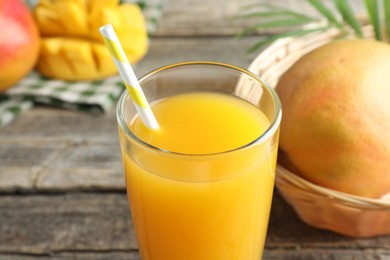 Photo of Tasty mango juice in glass and fresh fruits on table, closeup