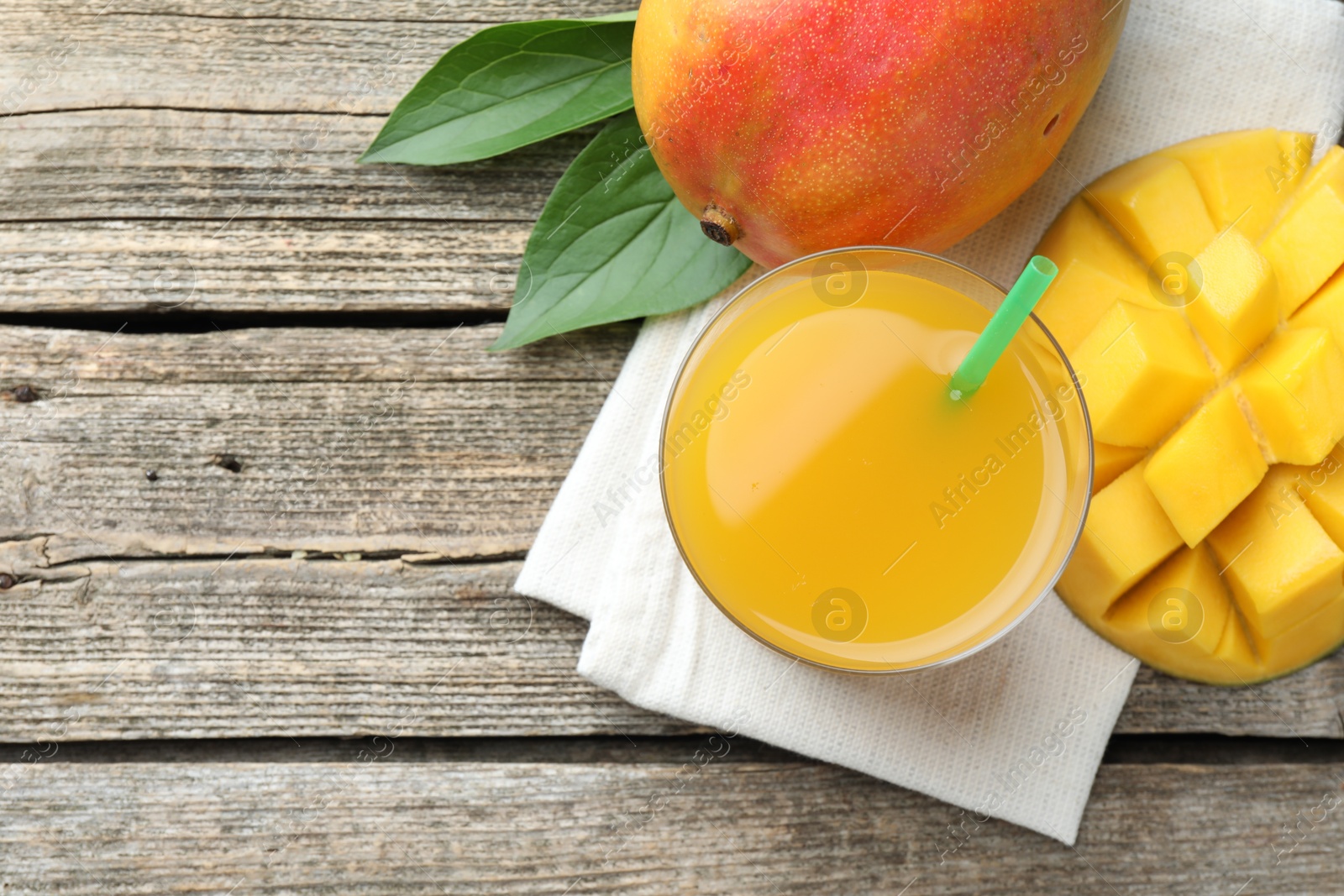 Tasty mango juice in glass, fresh fruits and leaves on wooden table, flat lay. Space for text Photo of Tasty mango juice in glass, fresh fruits and leaves on wooden table, flat lay. Space for text
