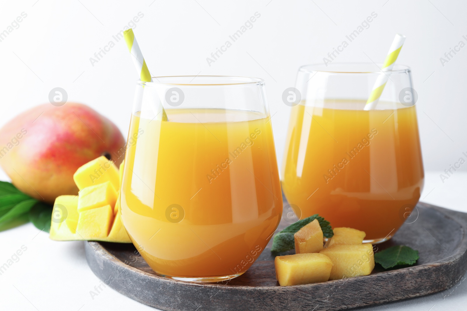 Tasty mango juice in glasses and fresh fruits on white table, closeup Photo of Tasty mango juice in glasses and fresh fruits on white table, closeup