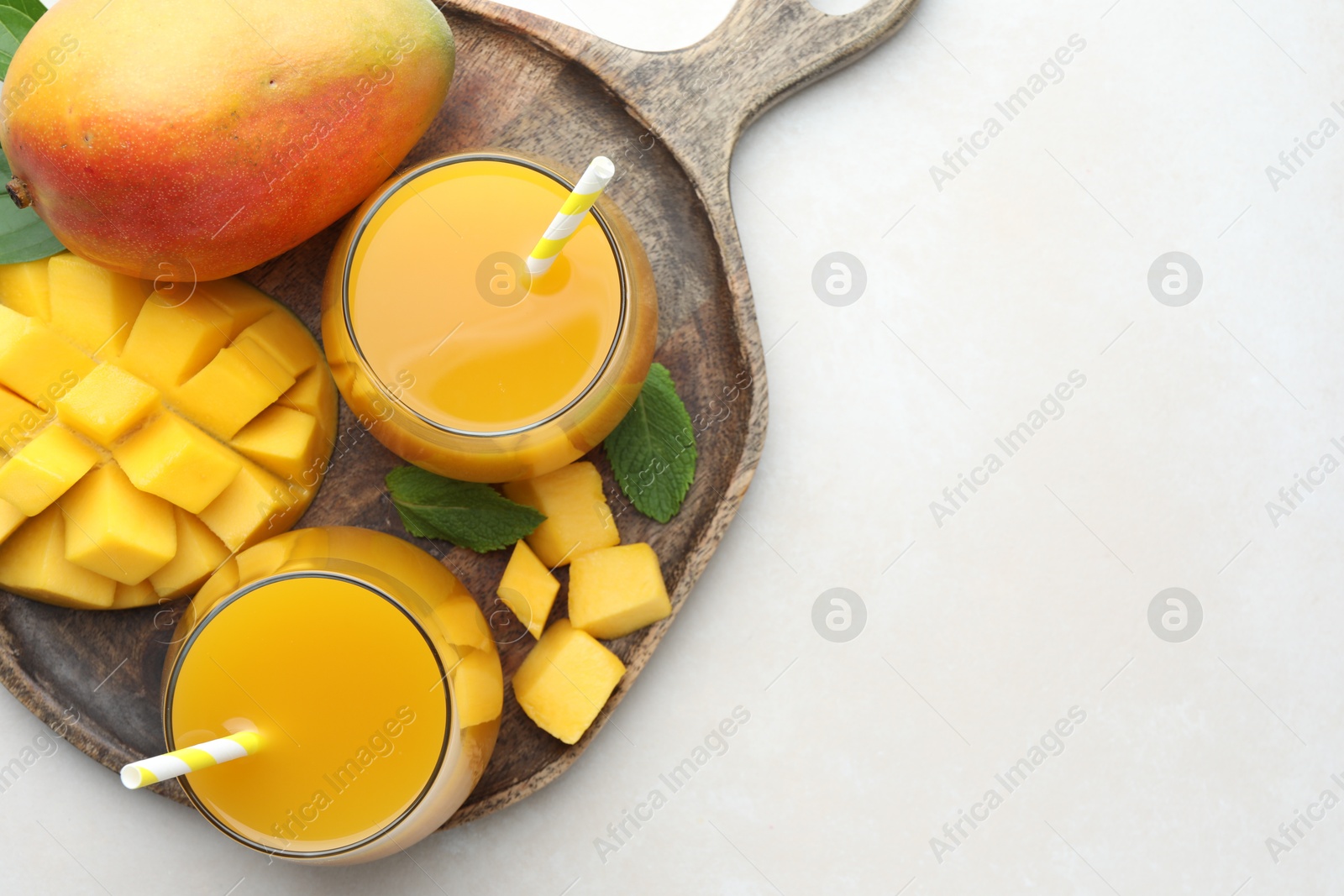 Tasty mango juice in glasses, fresh fruits and mint on white table, top view. Space for text Photo of Tasty mango juice in glasses, fresh fruits and mint on white table, top view. Space for text