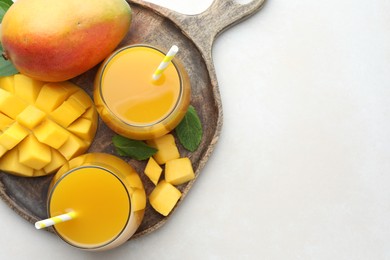 Photo of Tasty mango juice in glasses, fresh fruits and mint on white table, top view. Space for text