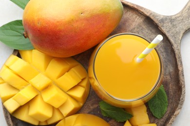 Photo of Tasty mango juice in glass, fresh fruits, green leaves and mint on table, top view