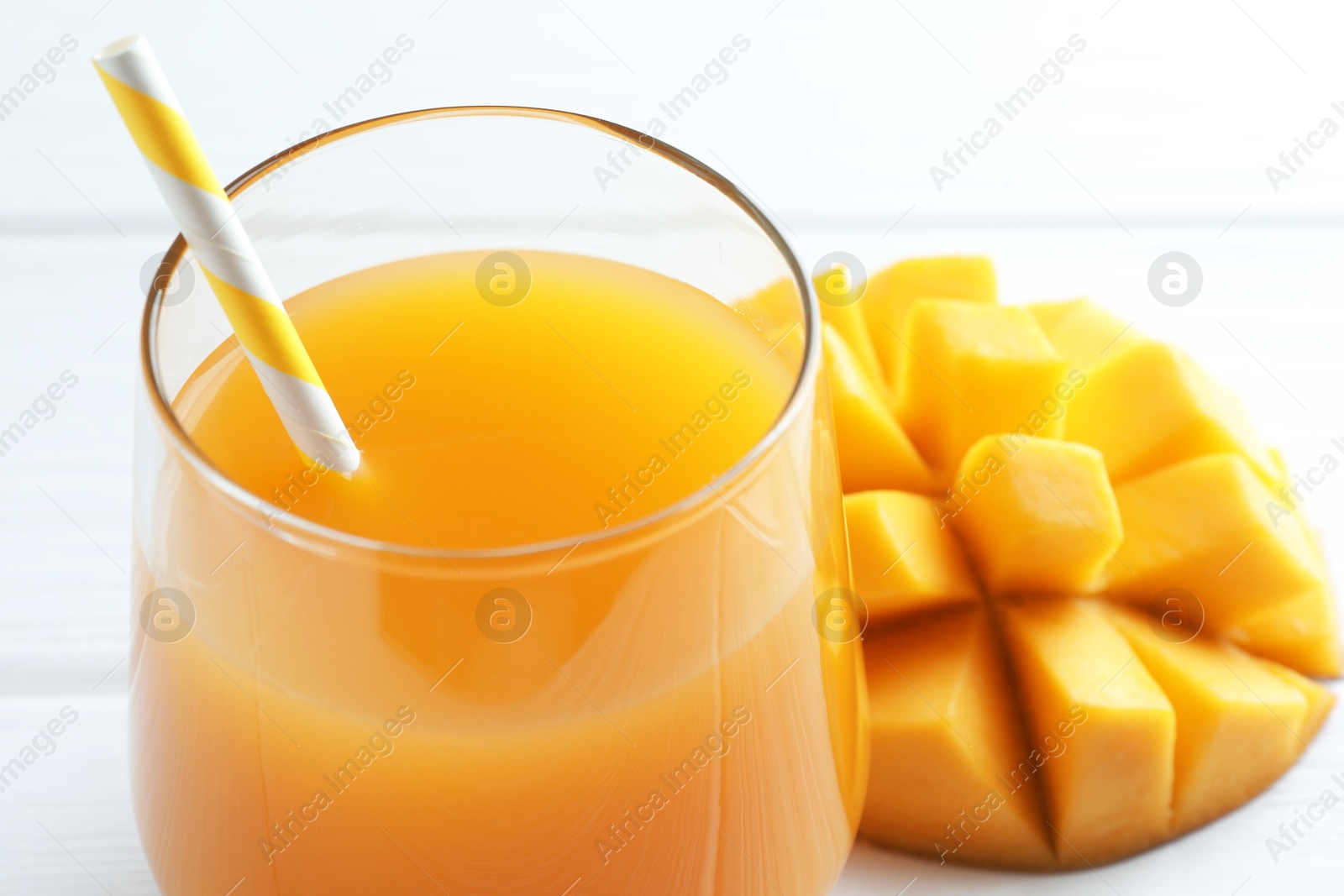 Tasty mango juice in glass and fresh fruit on white table, closeup Photo of Tasty mango juice in glass and fresh fruit on white table, closeup