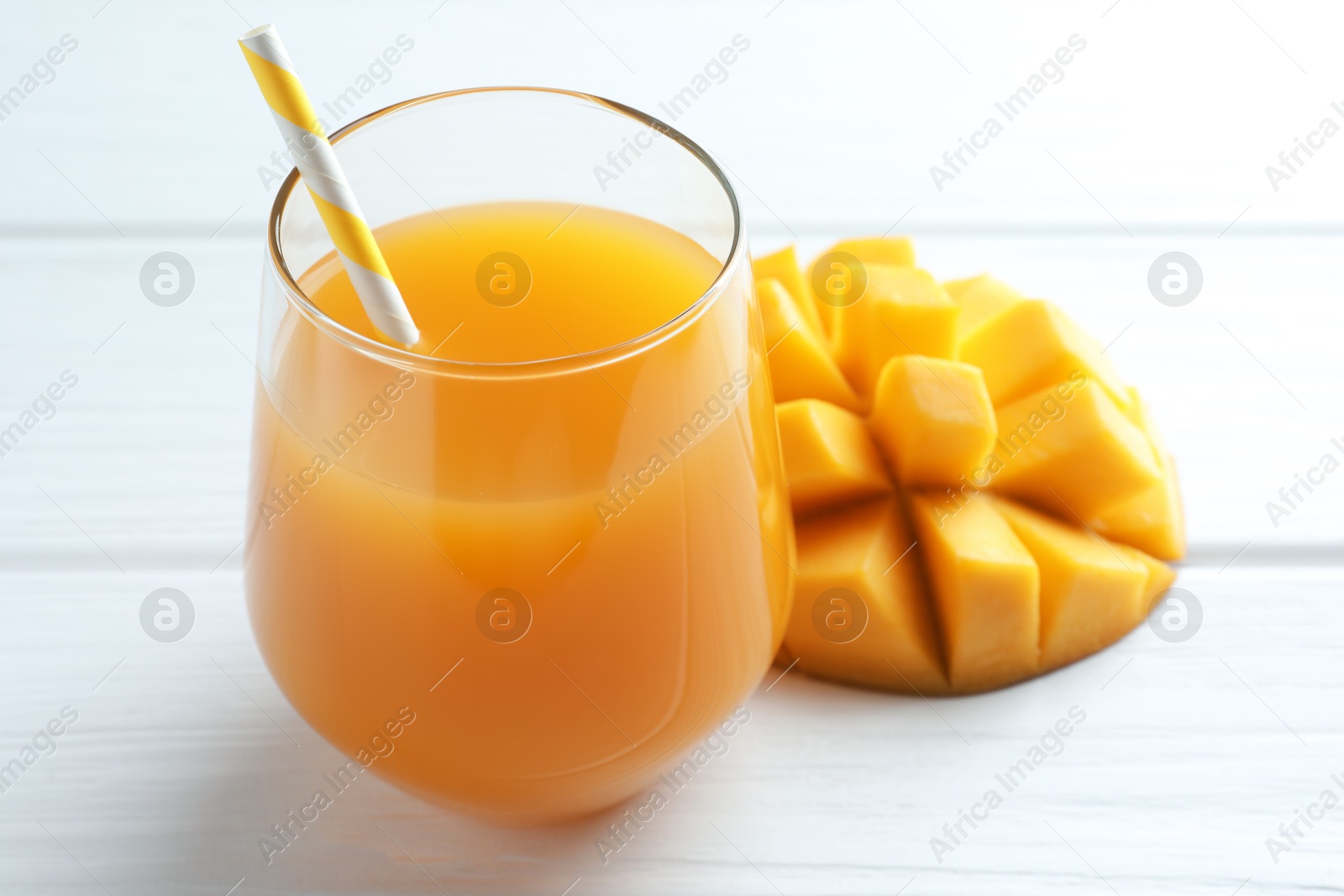 Tasty mango juice in glass and fresh fruit on white wooden table, closeup Photo of Tasty mango juice in glass and fresh fruit on white wooden table, closeup