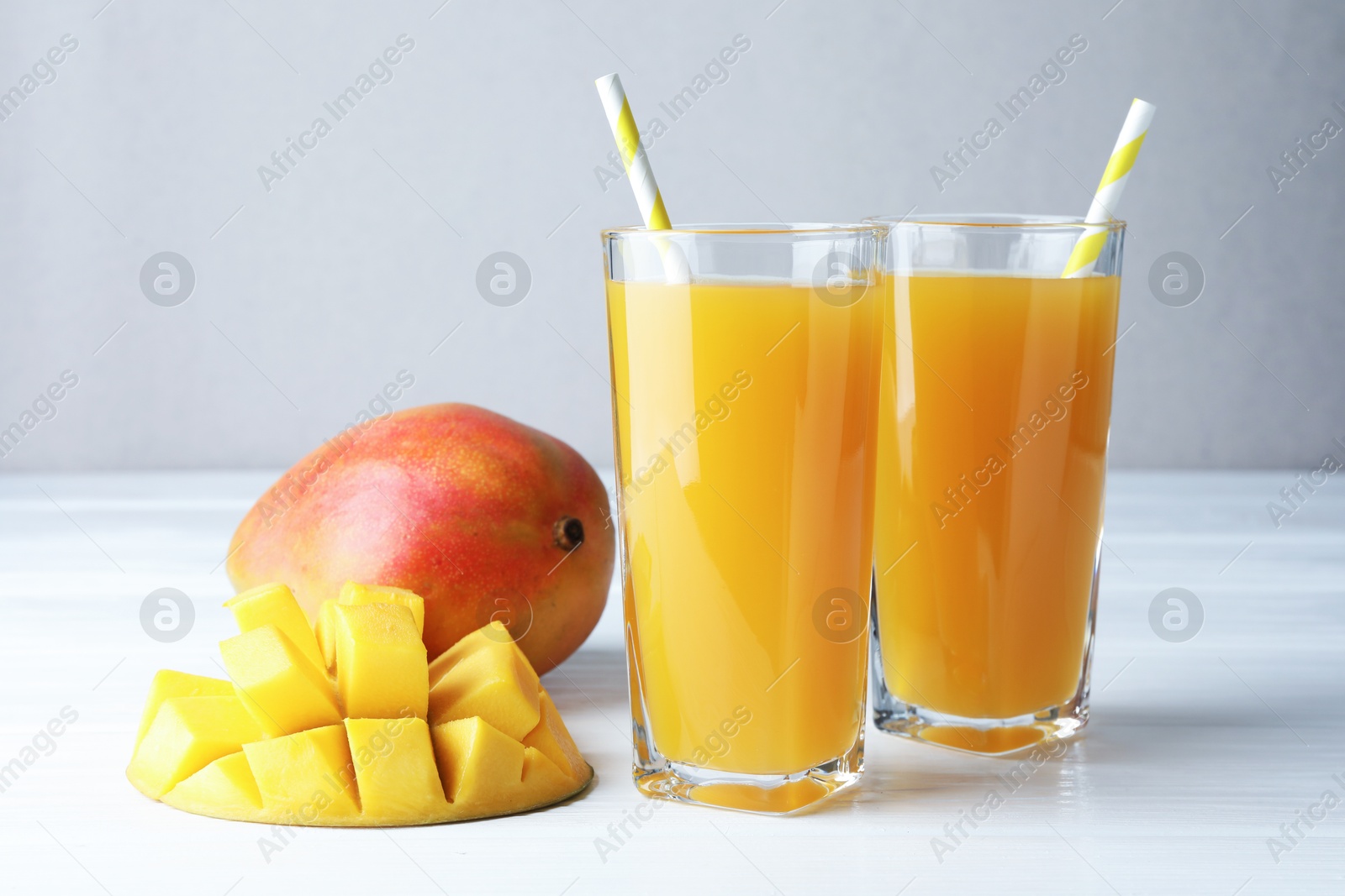Tasty mango juice in glasses and fresh fruits on white wooden table, closeup Photo of Tasty mango juice in glasses and fresh fruits on white wooden table, closeup