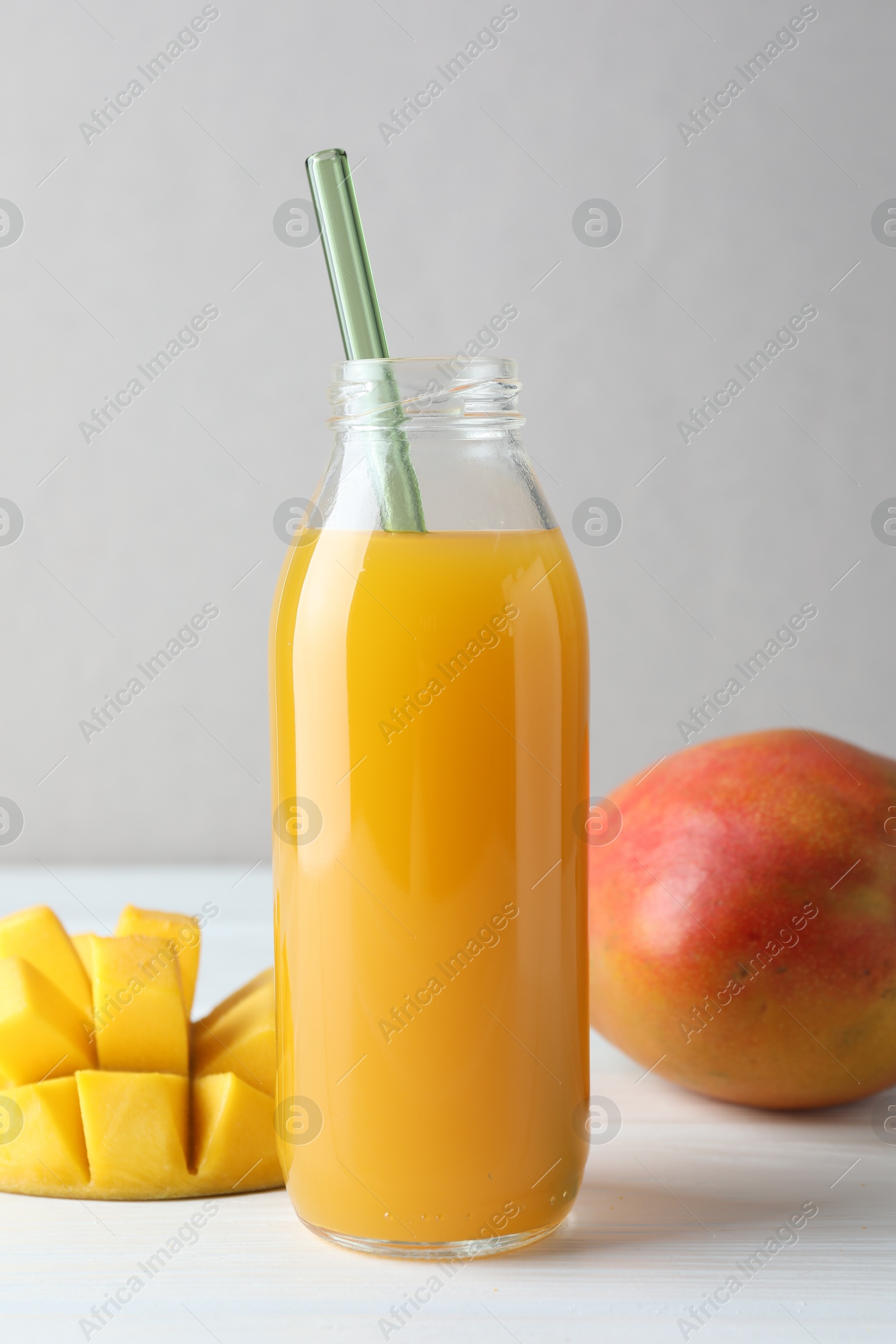 Tasty mango juice in glass bottle and fresh fruits on white wooden table, closeup Photo of Tasty mango juice in glass bottle and fresh fruits on white wooden table, closeup