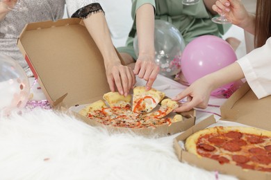Photo of Pajama party. Friends eating pizza on bed at home, closeup
