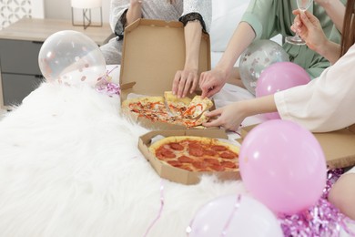 Photo of Pajama party. Friends eating pizza on bed at home, closeup