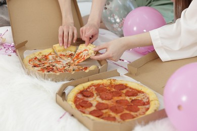 Photo of Pajama party. Friends eating pizza on bed at home, closeup
