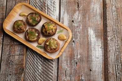 Photo of Delicious stuffed mushrooms with melted cheese, garlic and dill on color wooden table, top view. Space for text