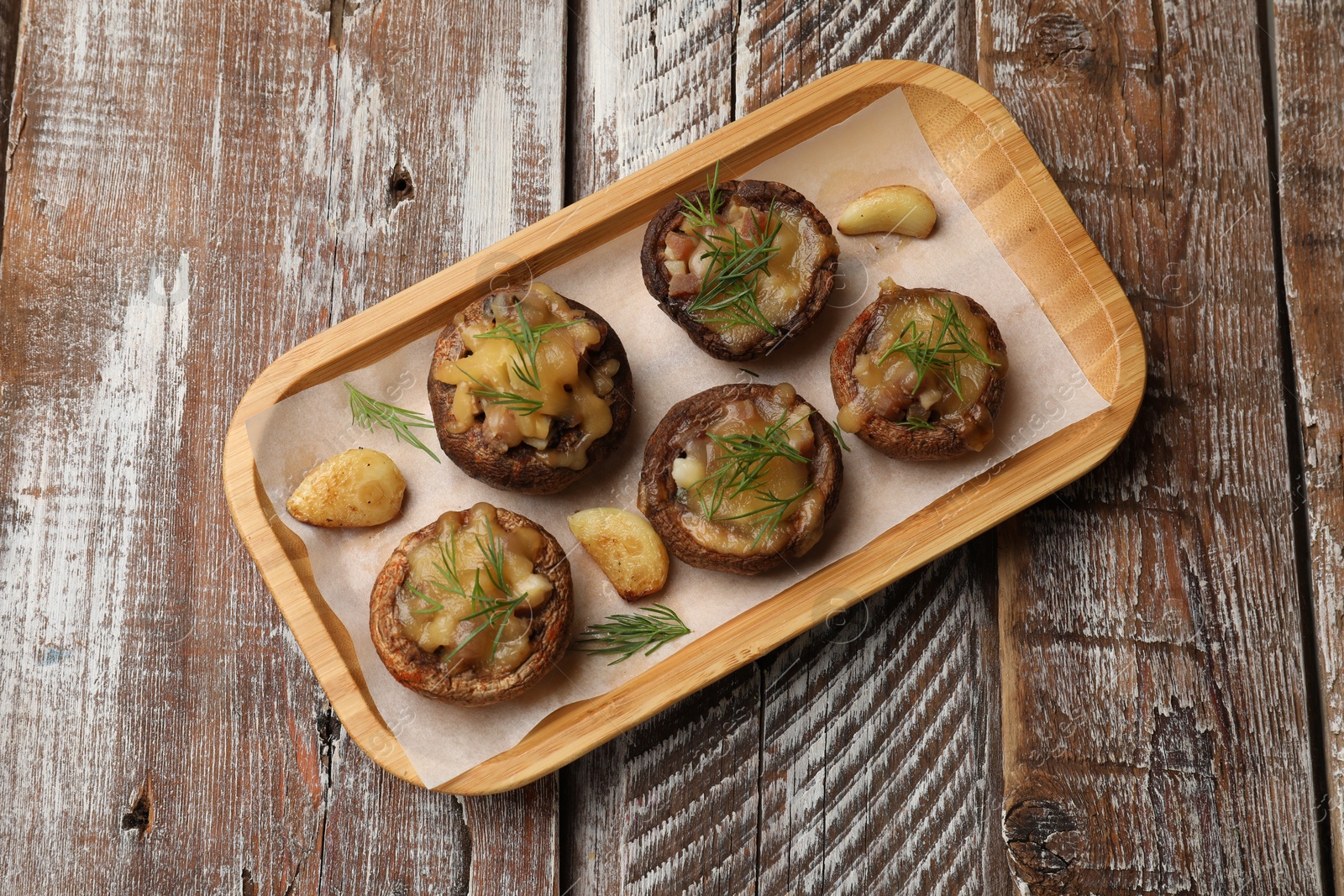 Delicious stuffed mushrooms with melted cheese, garlic and dill on color wooden table, top view Photo of Delicious stuffed mushrooms with melted cheese, garlic and dill on color wooden table, top view
