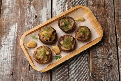 Photo of Delicious stuffed mushrooms with melted cheese, garlic and dill on color wooden table, top view