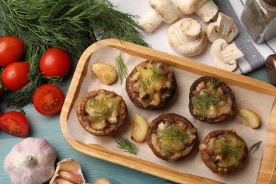 Photo of Delicious stuffed mushrooms and products on light blue wooden table, flat lay