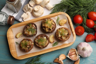 Photo of Delicious stuffed mushrooms and products on light blue wooden table, flat lay