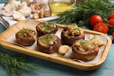 Photo of Delicious stuffed mushrooms with melted cheese, garlic and dill on light blue wooden table, closeup
