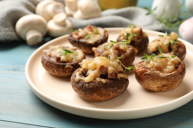 Photo of Delicious stuffed mushrooms with melted cheese and thyme on light blue wooden table, closeup