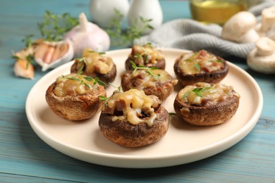 Photo of Delicious stuffed mushrooms with melted cheese and thyme on light blue wooden table, closeup