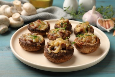 Photo of Delicious stuffed mushrooms with melted cheese and thyme on light blue wooden table, closeup