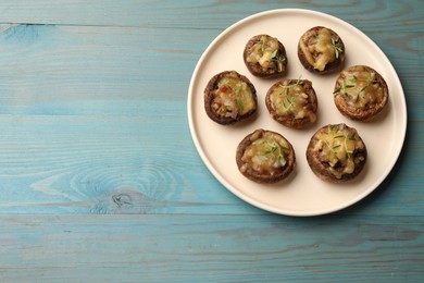 Photo of Delicious stuffed mushrooms with melted cheese and thyme on light blue wooden table, top view. Space for text