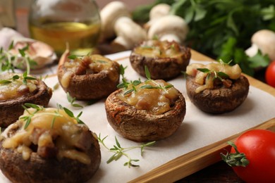 Photo of Delicious stuffed mushrooms with melted cheese and thyme on table, closeup