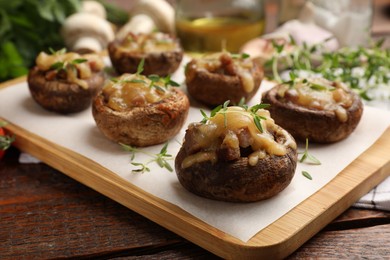 Photo of Delicious stuffed mushrooms with melted cheese and thyme on wooden table, closeup