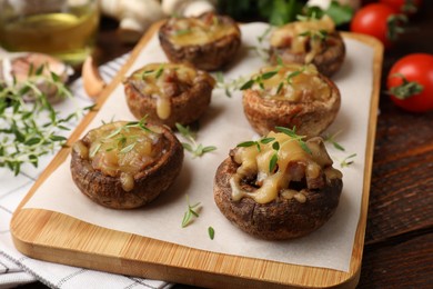 Photo of Delicious stuffed mushrooms with melted cheese and thyme on wooden table, closeup