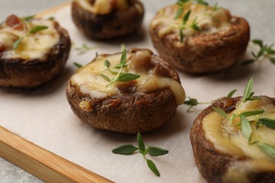 Photo of Delicious stuffed mushrooms with melted cheese and thyme on grey table, closeup