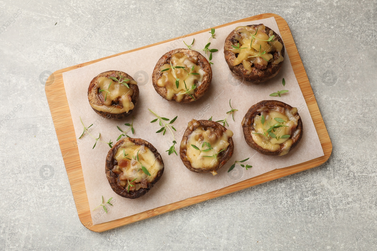 Delicious stuffed mushrooms with melted cheese and thyme on grey textured table, top view Photo of Delicious stuffed mushrooms with melted cheese and thyme on grey textured table, top view