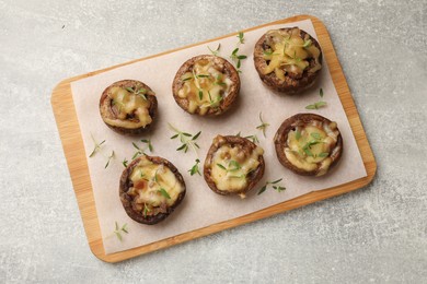 Photo of Delicious stuffed mushrooms with melted cheese and thyme on grey textured table, top view