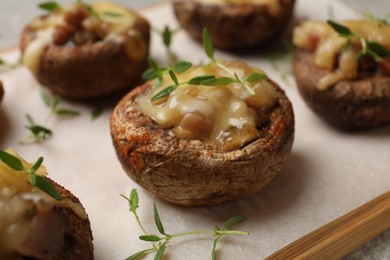 Photo of Delicious stuffed mushrooms with melted cheese and thyme on table, closeup