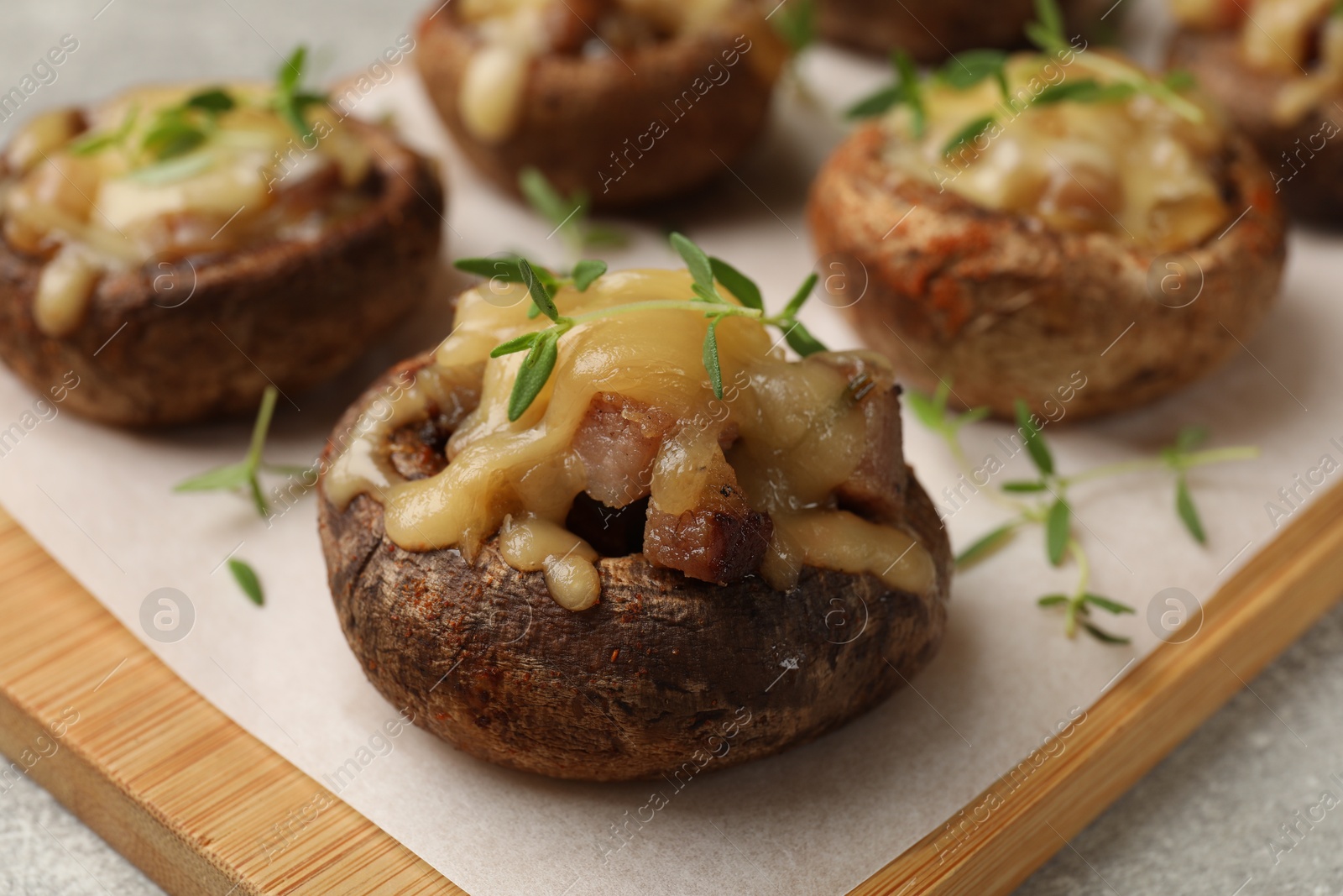 Photo of Delicious stuffed mushrooms with melted cheese and thyme on grey table, closeup