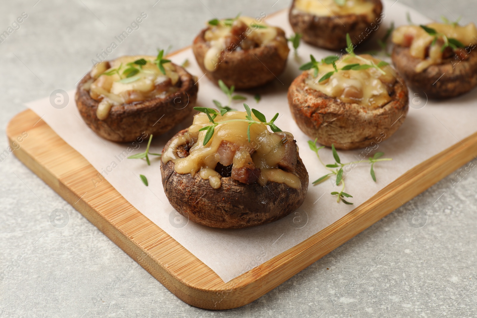 Delicious stuffed mushrooms with melted cheese and thyme on grey textured table, closeup Photo of Delicious stuffed mushrooms with melted cheese and thyme on grey textured table, closeup