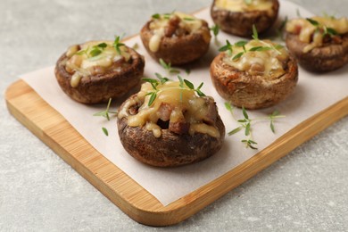 Photo of Delicious stuffed mushrooms with melted cheese and thyme on grey textured table, closeup