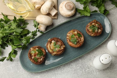 Photo of Delicious stuffed mushrooms with melted cheese and parsley on grey textured table, flat lay